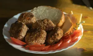 Talerz z kotletami mielonymi, kromkami chleba, pomidorami i serem. Idealny na szybki obiad, choć warto sprawdzić kotlet mielony kcal.