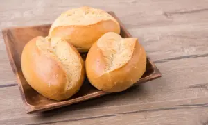 Trzy świeże bułki pszenne na drewnianej desce. Zastanawiasz się nad ich kcal?