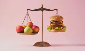Waga pokazuje nierównowagę: owoce po jednej stronie, burger po drugiej. Zastanawiasz się nad zakwaszeniem organizmu objawy?