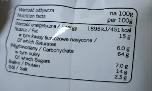 Etykieta z wartościami odżywczymi: 451 kcal na 100g. Tłuszcz 15g, węglowodany 64g, białko 7g. Idealne na 7days kcal.