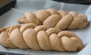 Dwie plecione chałki na papierze do pieczenia. Zastanawiasz się nad chałka kcal?