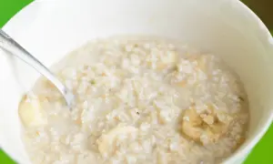 Owsianka z bananem w białej misce, z łyżeczką. Pytanie: ile trwa zapalenie żołądka?