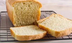 Świeżo upieczony chleb tostowy na kratce, z kilkoma kromkami obok. Idealny na śniadanie, ale warto sprawdzić chleb tostowy kcal.