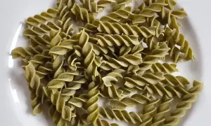Zielone fusilli, czyli makaron z zielonego groszku, ułożone na białym talerzu.