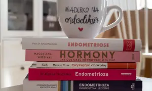 Stos książek o endometriozie, w tym "Endometrioza: diagnostyka i leczenie", z kubkiem "Wiaderko na endoeliksir".