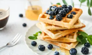 Stos gofrów z jagodami i miodem. Zastanawiasz się, ile kcal ma gofr? Ten deser wygląda pysznie!