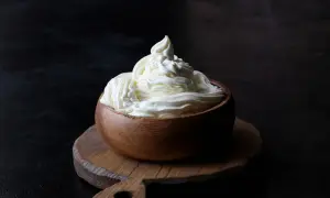 Kremowy mascarpone w drewnianej miseczce, idealny do deserów. Warto sprawdzić mascarpone kcal przed przygotowaniem słodkości.