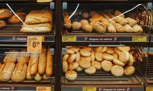 Na półkach sklepowych widać świeże pieczywo: bagietki, bułki i chlebki. Obok znajduje się etykieta z napisem "Biedronka", sugerująca, że to bułka o niskim IG, idealna dla dbających o linię.