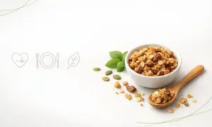 Misternie przygotowana granola w miseczce i na drewnianej łyżce. Czy granola jest zdrowa? Z pewnością tak, gdy zawiera płatki, orzechy i nasiona.