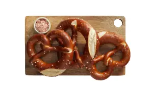 Trzy apetyczne precle z solą na desce, idealne na przekąskę. Zastanawiasz się nad precel Lidl kcal?