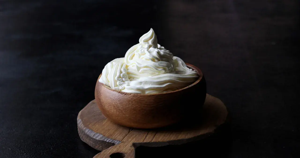 Kremowy mascarpone w drewnianej miseczce, idealny do deserów. Warto sprawdzić mascarpone kcal przed przygotowaniem słodkości.