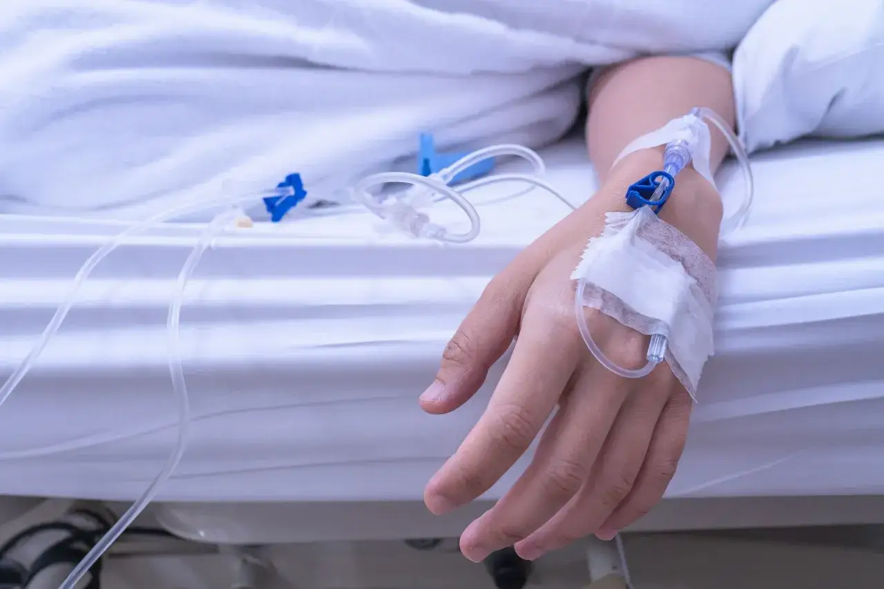 Ręka pacjenta z wenflonem, podłączona do kroplówki. Może to być leczenie hipernatremii.
