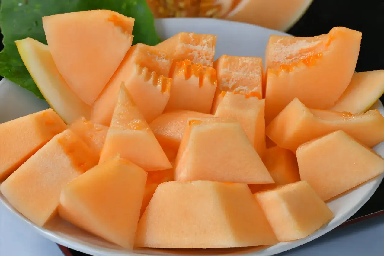 Kawałki pomarańczowego melona na talerzu. Ten owoc ma niski melon indeks glikemiczny, co czyni go zdrową przekąską.