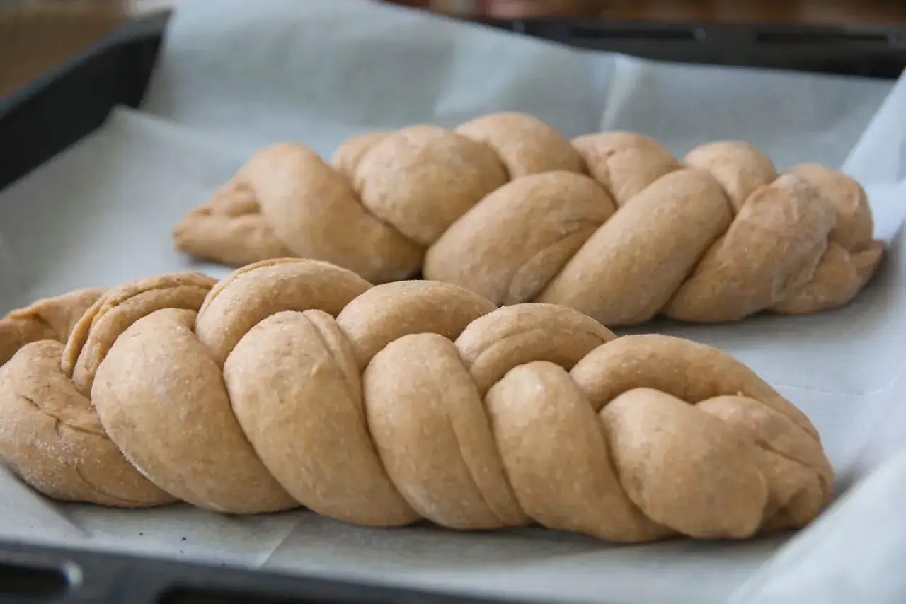 Dwie plecione chałki na papierze do pieczenia. Zastanawiasz się nad chałka kcal?