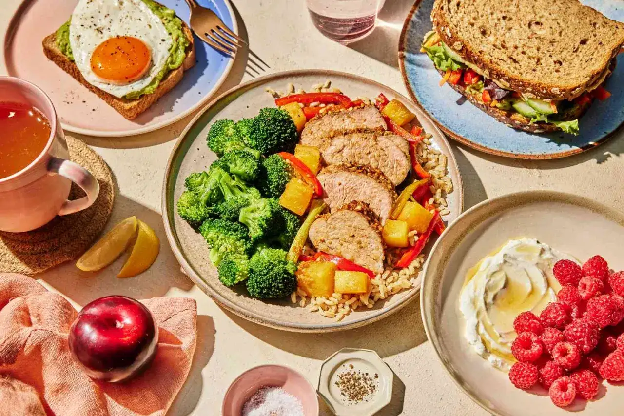 Zdrowe posiłki na talerzach: pieczony łosoś z brokułami, ryżem i ananasem, kanapka z warzywami, tosty z awokado i jajkiem, jogurt z malinami. Idealne na dieta 1200 kcal.