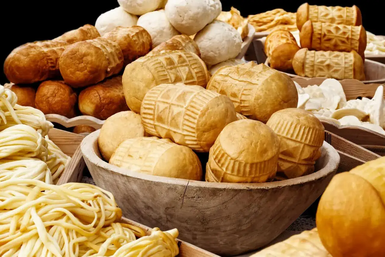 Górskie sery, w tym oscypek, kuszą smakiem. Zastanawiasz się nad oscypek kcal? Oto bogactwo serów w drewnianych naczyniach.