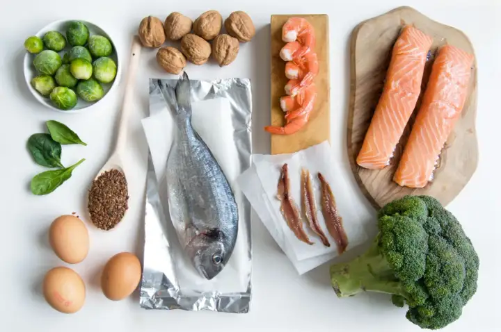 Różnorodne produkty bogate w omega 3: łosoś, sardele, krewetki, ryba morska, orzechy, siemię lniane, brokuły, brukselka, szpinak i jajka.
